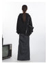 Black oversized hoodie with curved pocket design and metal snaps, paired with gray maxi skirt, shown from back view