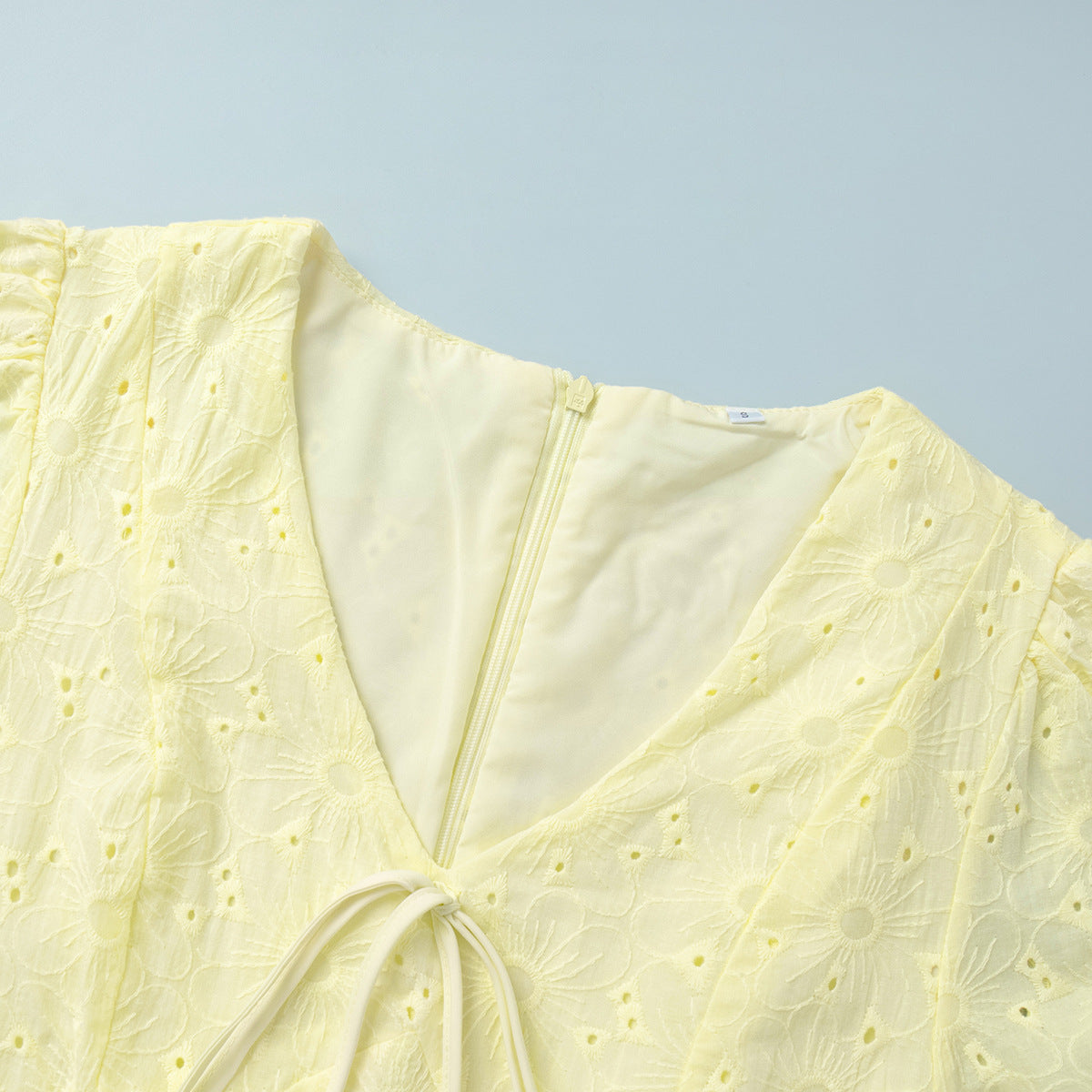 Yellow dress with floral embroidery on a light blue background