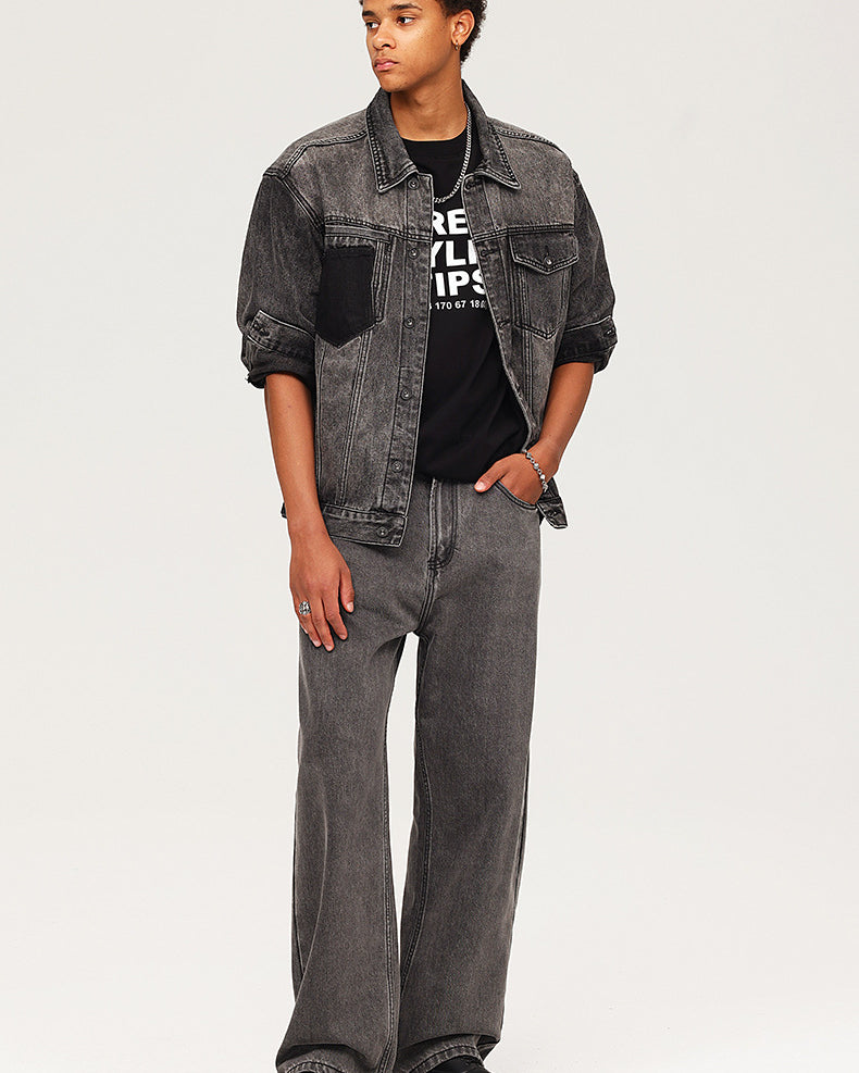 Young model wearing washed black denim jacket over graphic tee with matching wide-leg jeans and chunky boots
