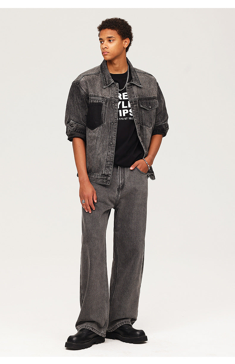 Young model wearing washed black denim jacket over graphic tee with matching wide-leg jeans and chunky boots