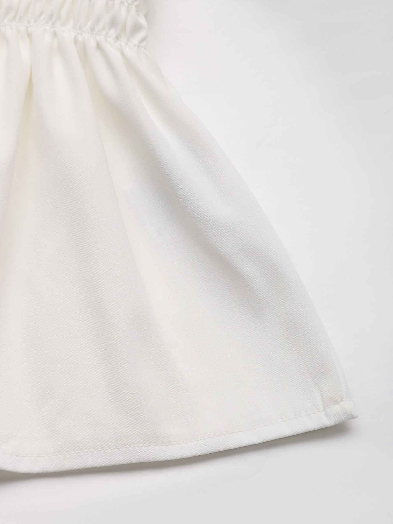 Close-up of the hem of the white peplum blouse, highlighting the soft flowy fabric.
