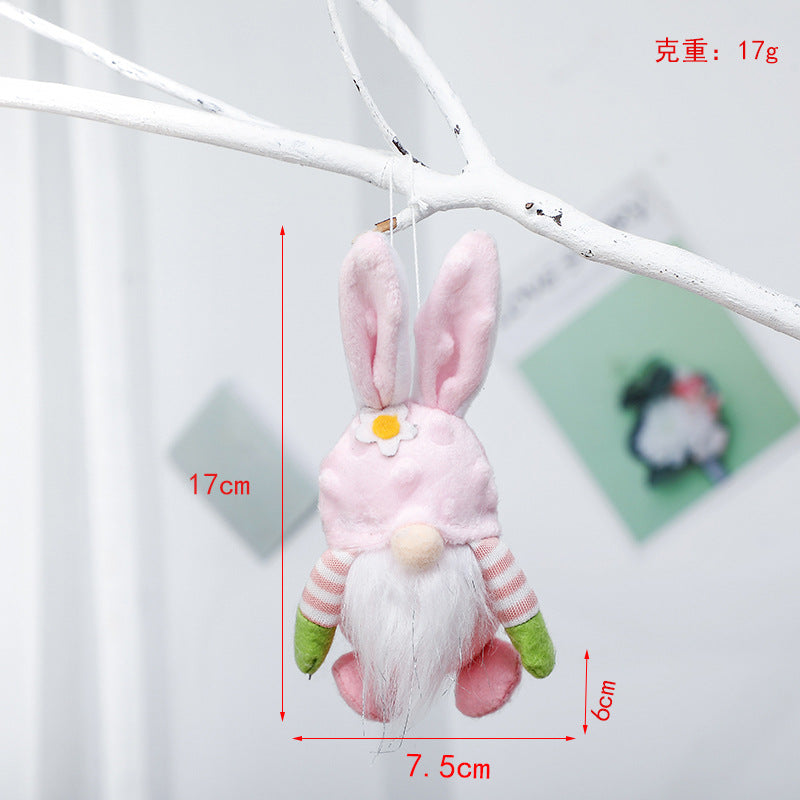 Pink plush bunny gnome with flower detail, hanging from a white branch. Dimensions: 17cm height, 7.5cm width, 6cm depth, weight 17g.