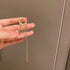 Gold ear cuff with pearls and chain held in hand, showing delicate design details