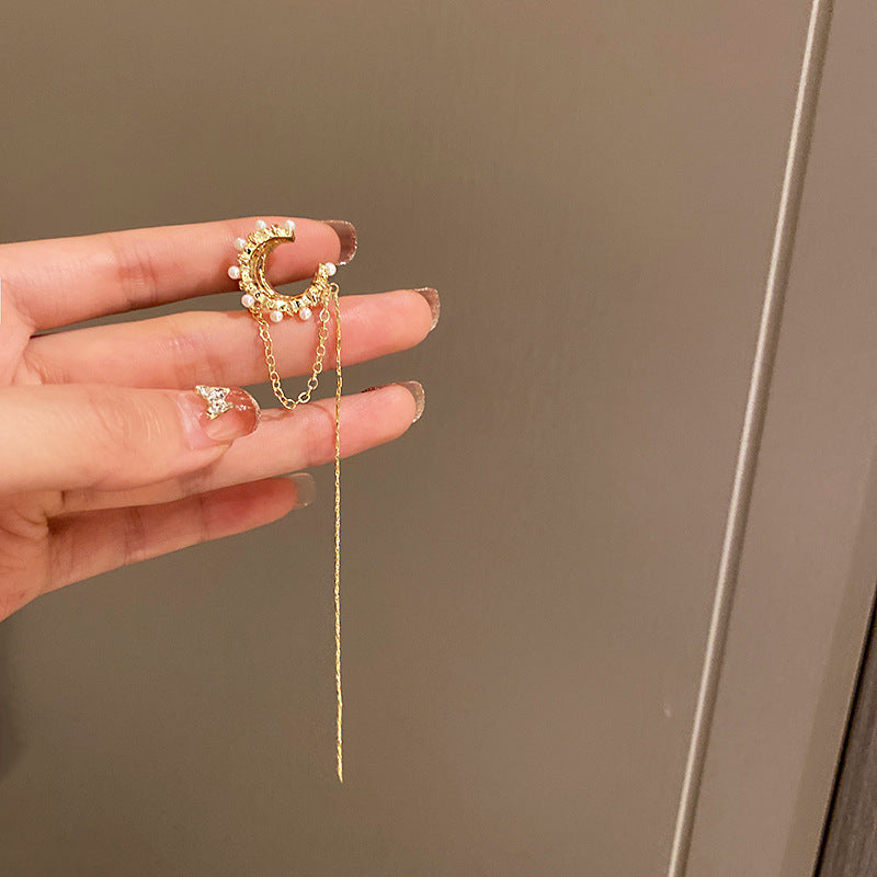 Gold ear cuff with pearls and chain held in hand, showing delicate design details
