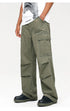 A person standing in olive green multi-pocket cargo pants with white HARSHandCRUEL tee and silver bracelet against white background
