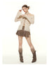 Dynamic pose showcasing cream off-shoulder sweater with distressed details and lace-up front. Paired with brown pleated mini skirt and brown leather boots with gathered socks