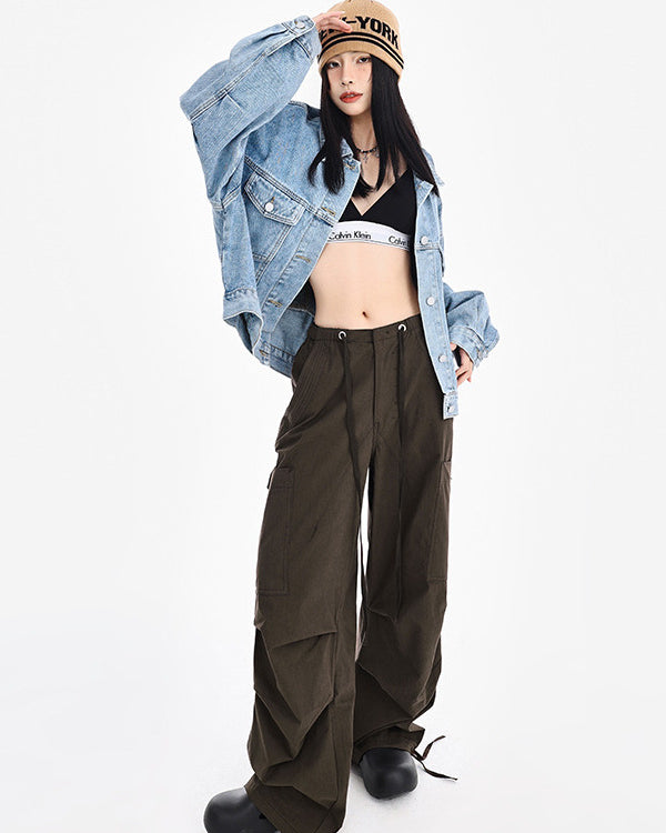 Model posing with hand on beanie, wearing oversized denim jacket, Calvin Klein sports bra, wide-leg cargo pants and chunky black boots
