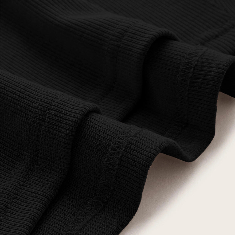 Black ribbed knit fabric close-up showing stretchy texture and hemmed edge details with decorative cross-stitching visible
