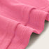Pink ribbed knit fabric close-up showing stretchy textile texture and finished edge with decorative cross-stitching detail