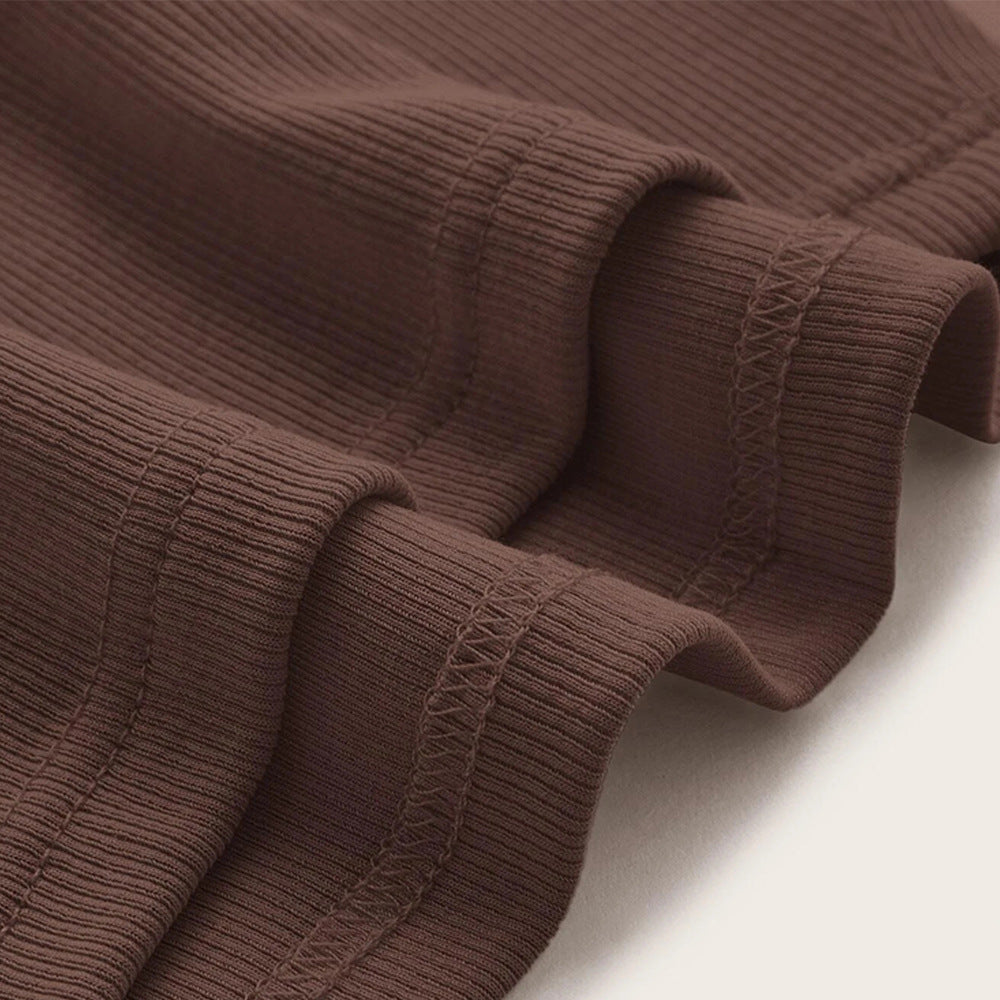 Brown ribbed knit fabric close-up showing stretchy texture and hemmed edge details with decorative cross-stitching visible