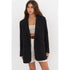Oversized black blazer with peaked lapels, styled over a cream bandeau top and white high-waisted shorts with a brown leather belt