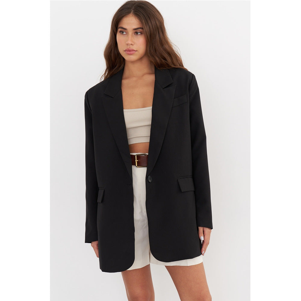 Oversized black blazer with peaked lapels, styled over a cream bandeau top and white high-waisted shorts with a brown leather belt