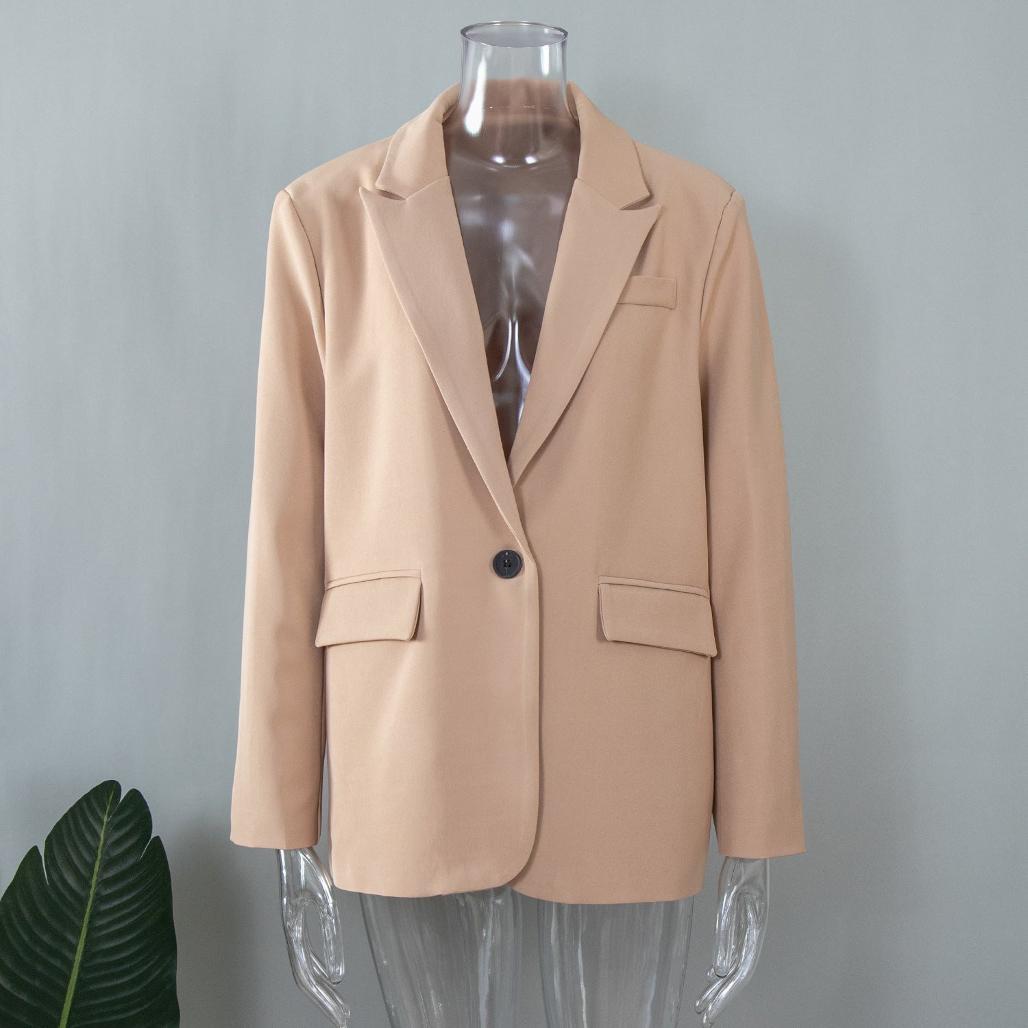 Beige oversized blazer displayed on a transparent mannequin, featuring classic tailoring with notched lapels and flap pockets