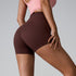 Brown athletic shorts with seamless design shown from side angle, styled with pink sports bra