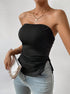 A model in black ribbed tube top with side ties paired with light wash jeans, wearing gold pendant necklace against white wall