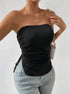 Close-up of model wearing black strapless ribbed top with side ties, gold necklace and chain strap handbag with light jeans