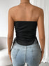 Back view of model showing black ribbed tube top with side drawstrings paired with light wash denim, gold neck chain