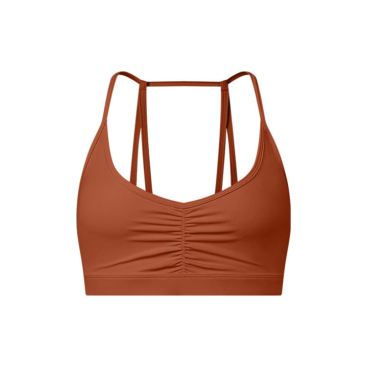 A terracotta strappy sports bra with ruched center detail and thin double-strap design shown against white background