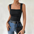 Woman wearing a black ribbed tank top with square neckline, styled with light jeans, black belt and layered necklaces