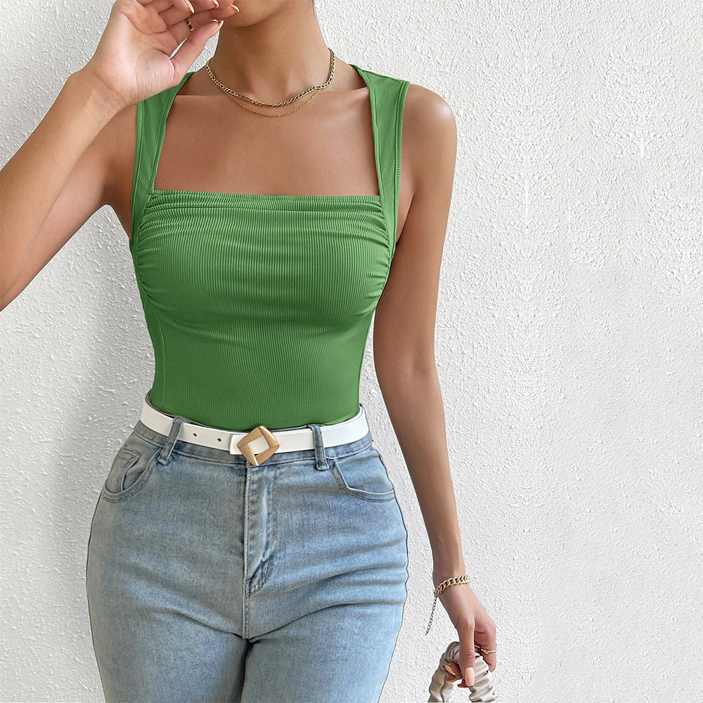 Woman wearing sage green square neck tank top with ruched bust detail and white belt with gold buckle