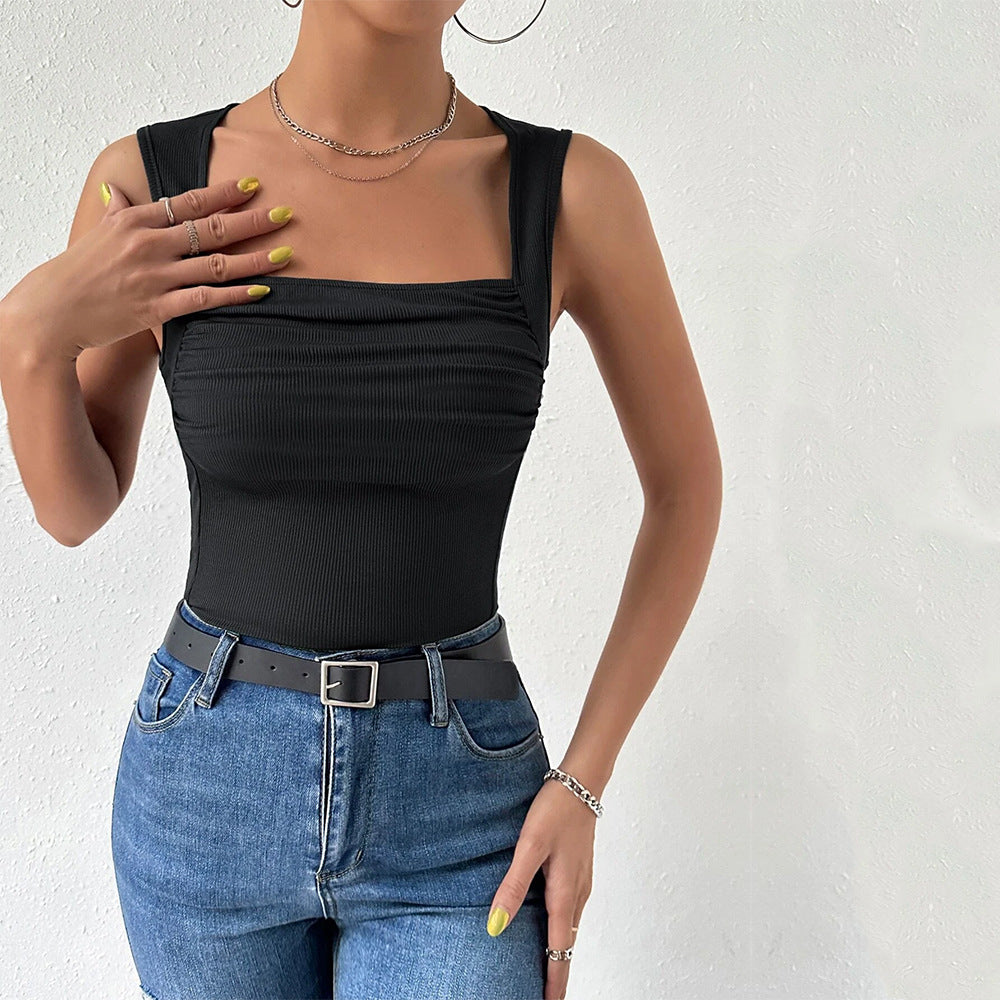 Close-up of black square neck tank with ruched detail, accessorized with gold chains and neon yellow nails
