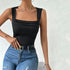 Woman wearing ribbed black tank top with square neckline, styled with belt and distressed denim