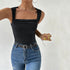 Woman in black square neck tank with ruched details and wide straps, wearing light jeans and silver jewelry