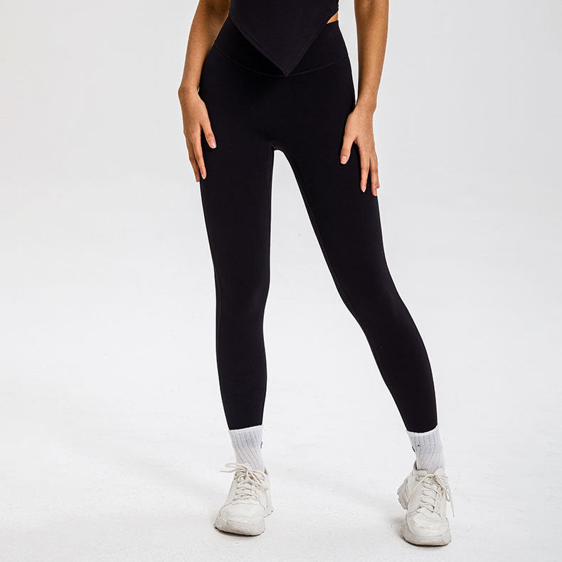 Model in black high-waisted leggings with white crew socks and white sneakers, standing on white background