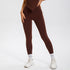 Model wearing chocolate brown high-waisted leggings with white socks and white athletic sneakers, studio lighting