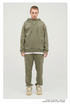 Male model with short hair wearing a sage green sweatsuit with hoodie, white undershirt, and matching joggers