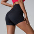 Black compression shorts with high waistband shown from side view, model wearing red sports top, gold nail polish detail
