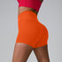 Orange compression shorts with high waist detail, paired with red sports top against neutral background