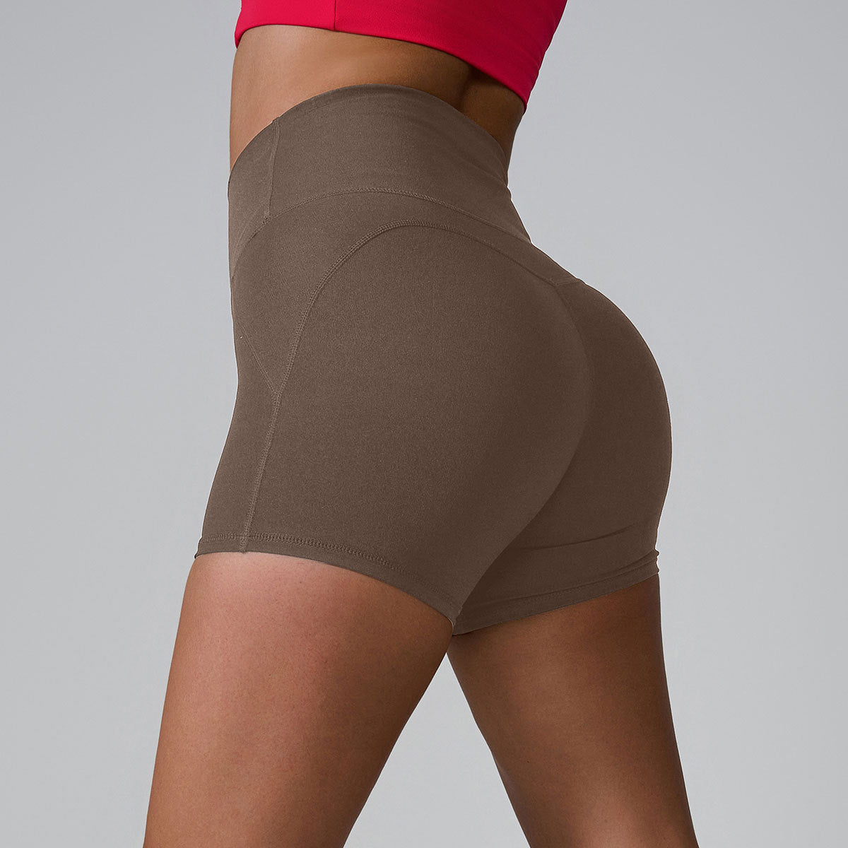 Taupe high-waisted compression shorts shown from side angle, styled with red sports top