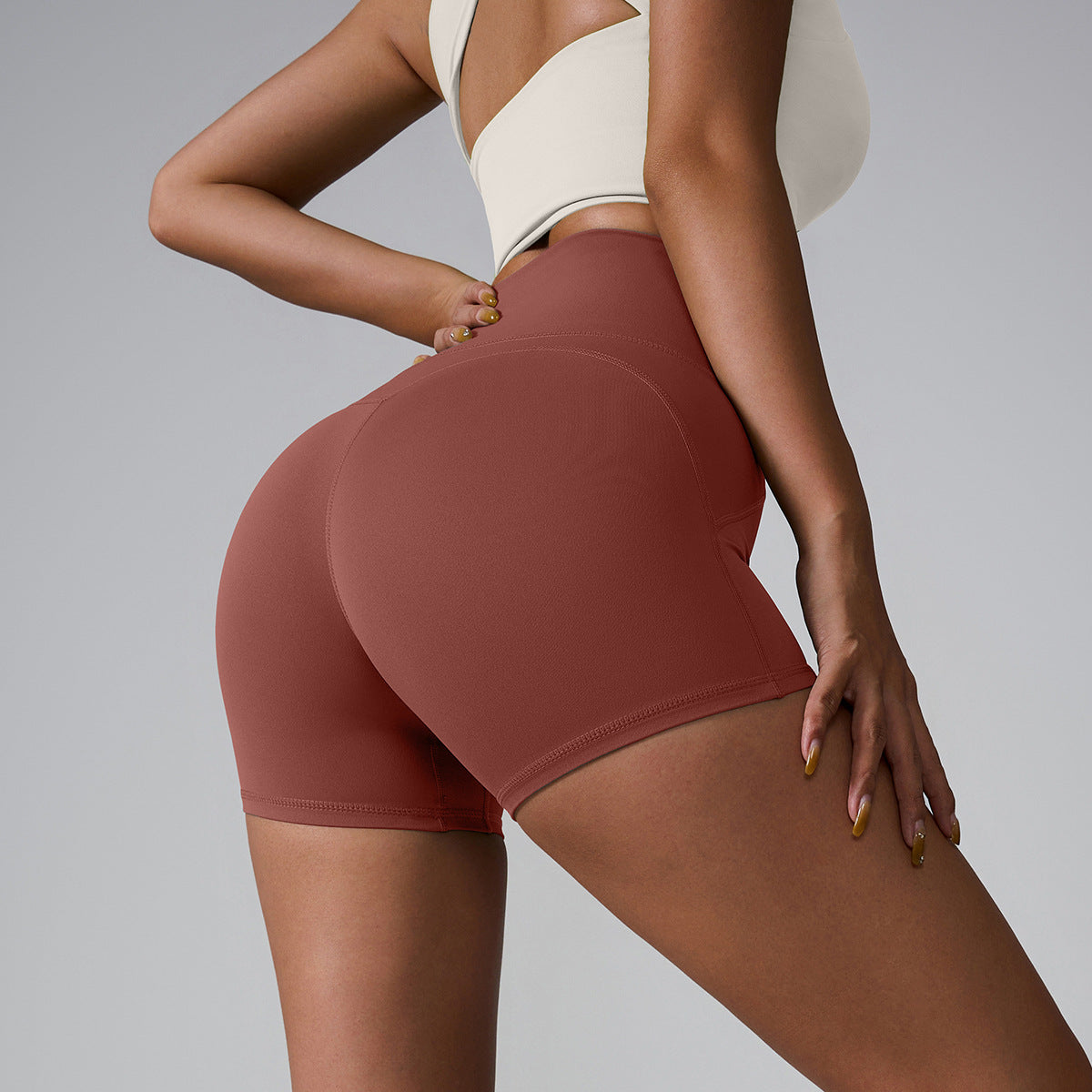 Mauve athletic shorts with seamless design, styled with cream sports top, side profile against gray backdrop
