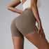 Taupe high-waisted compression shorts with contoured seams, paired with cream sports bra, side view