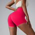 Hot pink seamless athletic shorts shown from side angle, styled with cream sports top against gray background