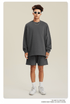Man in dark gray sweatshirt and shorts set with sunglasses, chain necklace and white sneakers