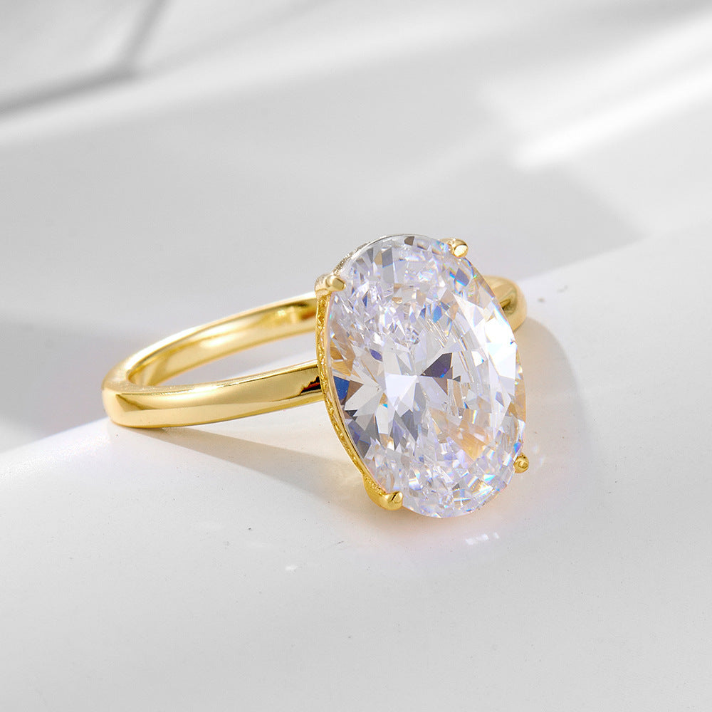A gold oval-cut diamond solitaire ring shown from side angle on white surface, featuring a brilliant crystal in four-prong setting