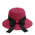 Rose red straw sun hat with a black ribbon bow, adding a pop of color to a stylish summer look.
