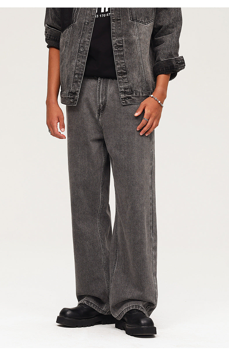 Side view close-up of relaxed-fit washed black jeans with silver bracelet detail, showing clean lines and casual styling