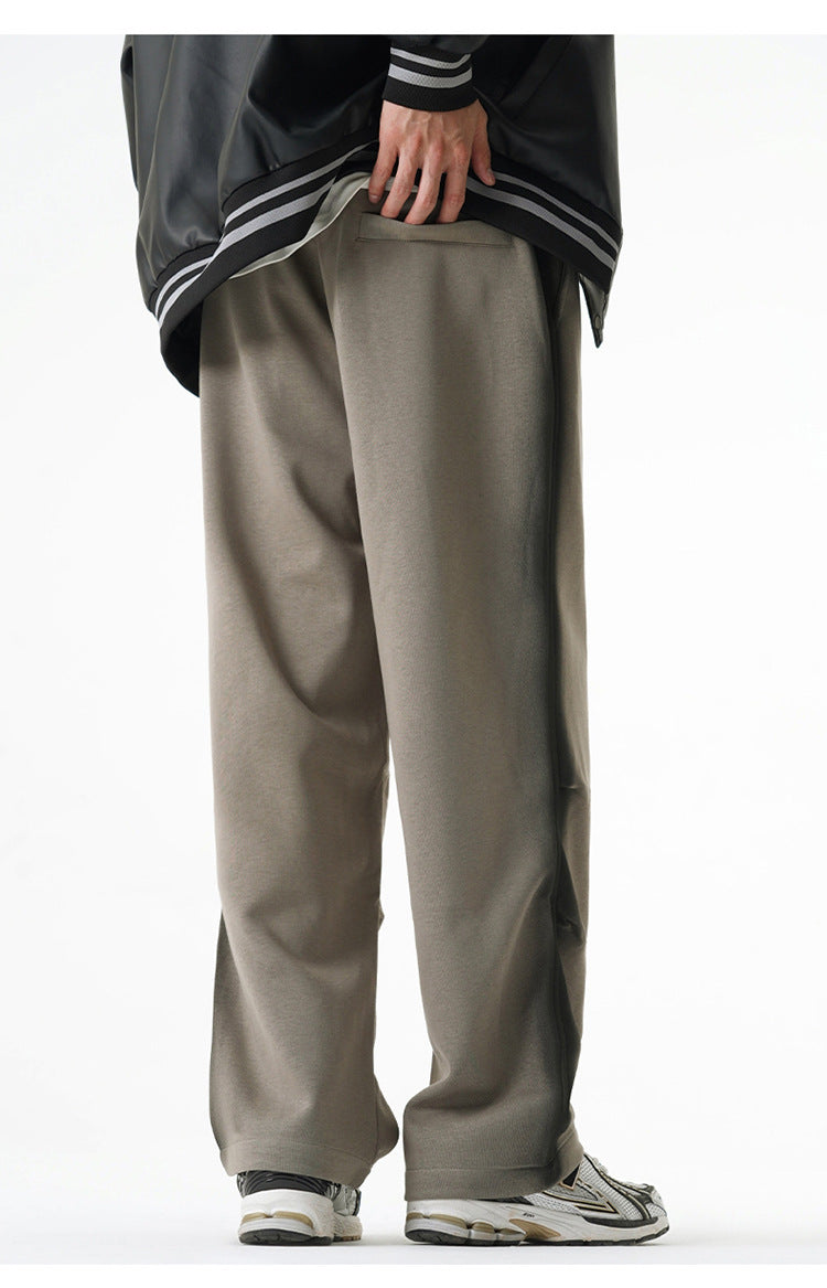 Back view of gray wide-leg pants with a pocket detail, paired with a black varsity jacket