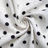 Swirled fabric close-up of a white polka dot dress, showing its smooth texture and breathable material.