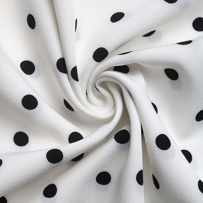 Swirled fabric close-up of a white polka dot dress, showing its smooth texture and breathable material.