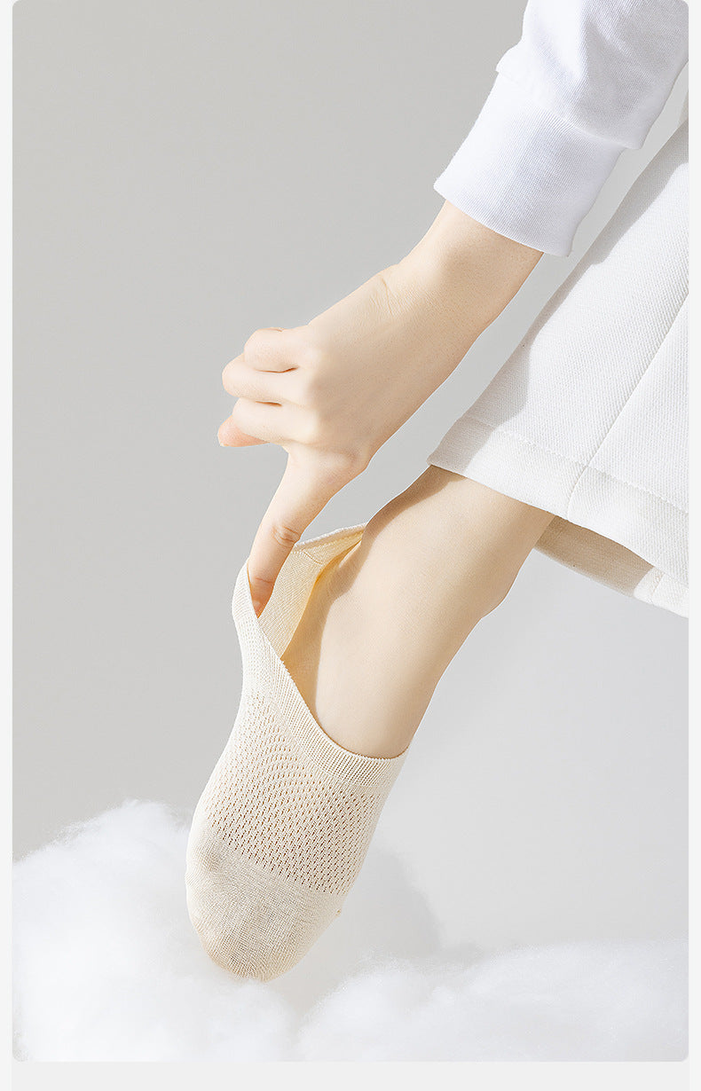 Cream-colored no-show sock being pulled on foot, showing elastic comfort band