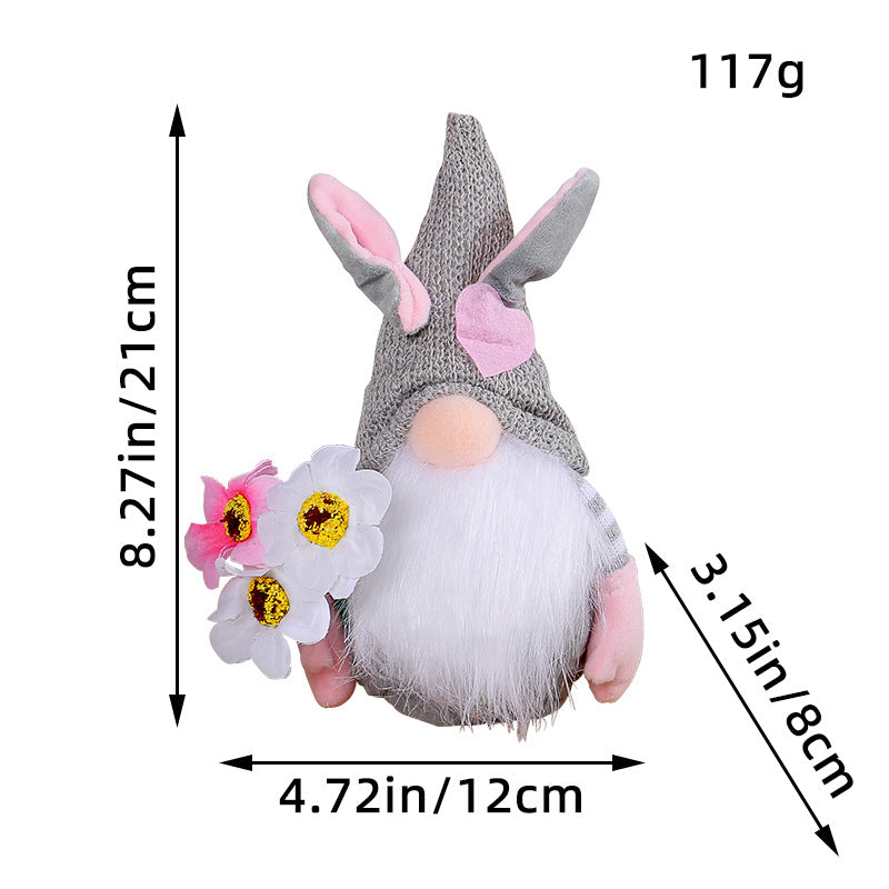 Easter gnome with an 8.27in (21cm) gray knitted hat, pink bunny ears, white beard, and holding white and pink flowers.