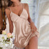 Woman in a champagne satin slip dress with a deep V-neck, near lace curtains