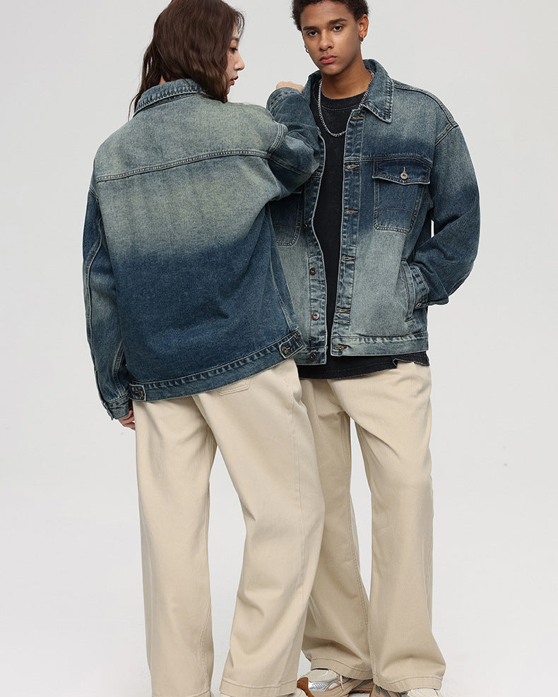 A woman with her back to camera and man facing forward pose against gray background. Both wearing gradient-wash denim jackets and beige wide-leg pants