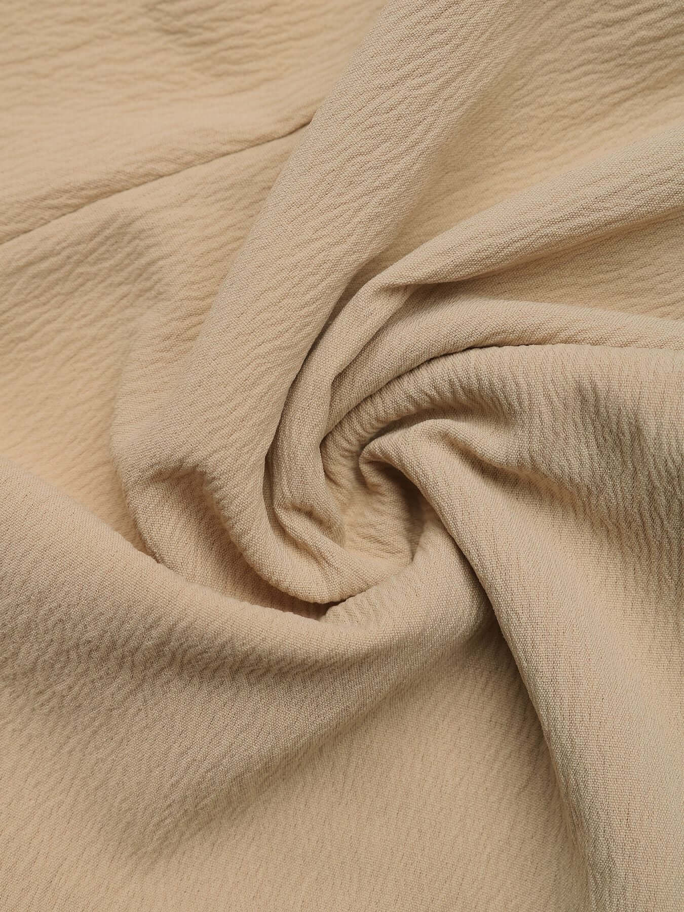 Fabric texture of beige high-waisted shorts, showcasing the soft, crinkled material.
