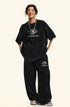 Model smiling in black Backstairs t-shirt and sweatpants set against white background