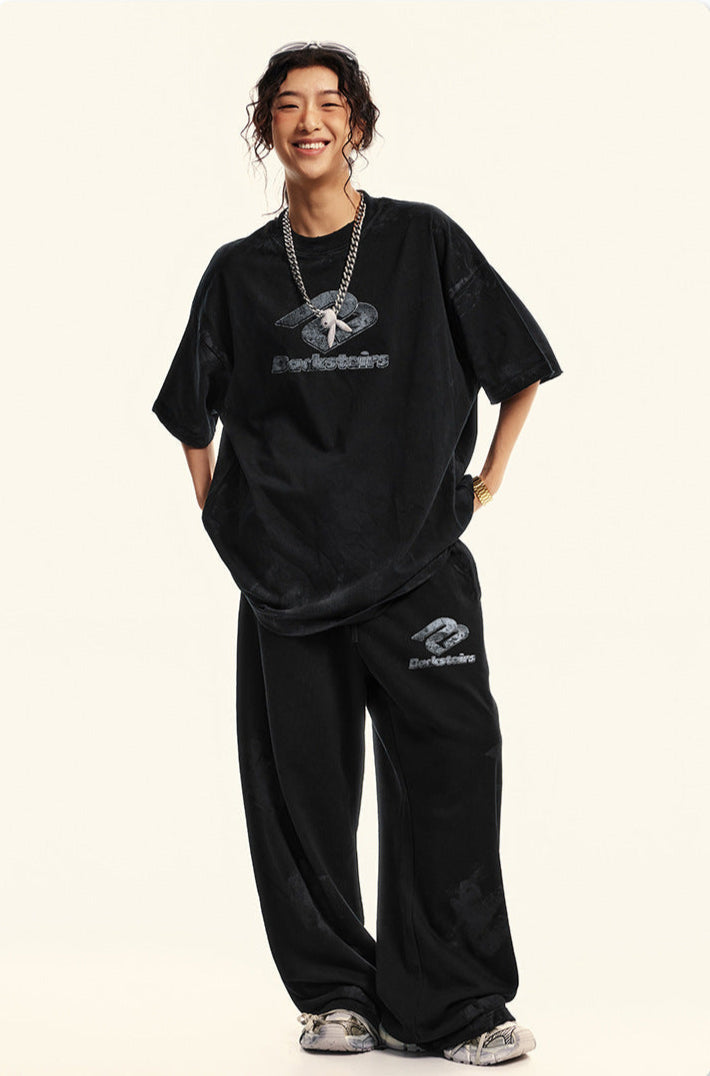 Model smiling in black Backstairs t-shirt and sweatpants set against white background